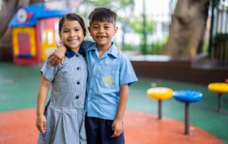 Two primary school friends in a school playground. Friendships and a growth mindset help to grow students' resilience.